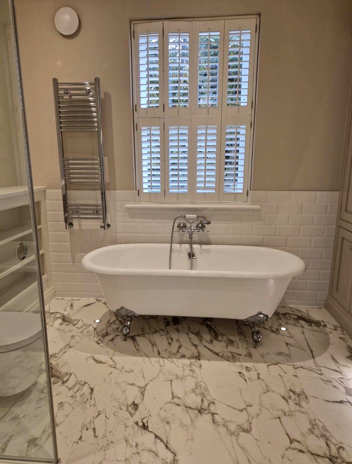 Master bathroom with freestanding roll-top bath and shutters